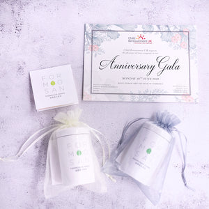 overhead shot of two white tea caddies wrapped in see through lace with certificate placed above them