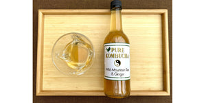 overhead shot of pure kombucha bottle on laid down next to glass containing its content