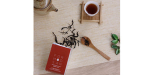 cup of red tea with box of tea leaves spilling leave onto table